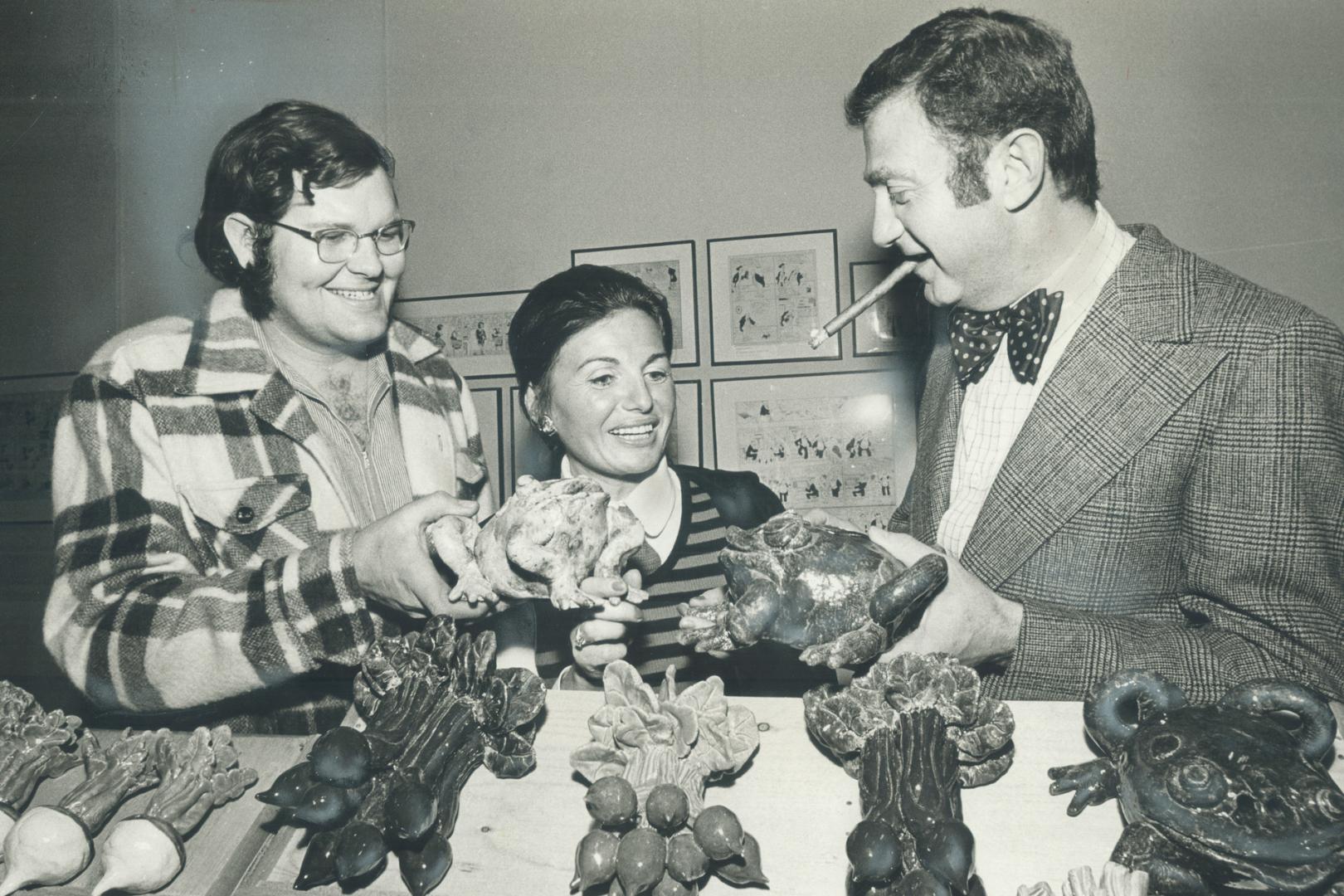 Artist David Gilhooly, left, shows his ceramic frogs and vegetables to Elizabeth Kady and John Zeldin at the art exhibit put together by the art renta(...)