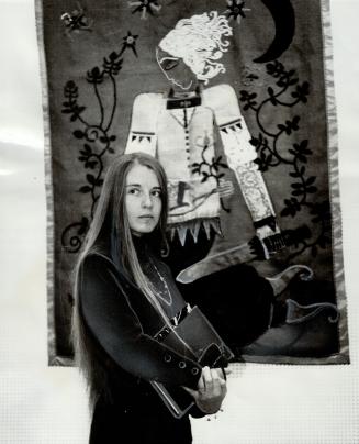 A young artist stands before some or her artistic work