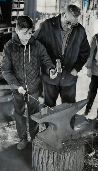 Blacksmithing is demonstrated by Norman Rose, who shows Edward Weinberg how to hammer a nail on the anvil