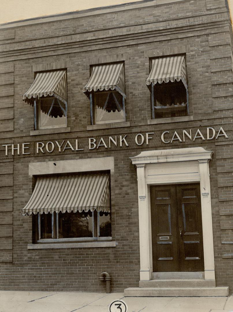 Tight view of façade of two-storey brick building with boldly striped fringed awnings over wind…