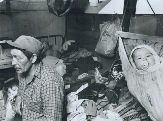 Baby Virgina Wischee sleeps in a hammock-style cradle slung over her parents' bed in this Tent City shack near Moosonee