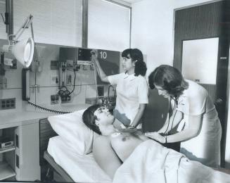 Intern Uldis Bite acts as patient while nurses Mila Lee, left, and Glenda Mulder check heartbeat and blood pressure on TV monitor