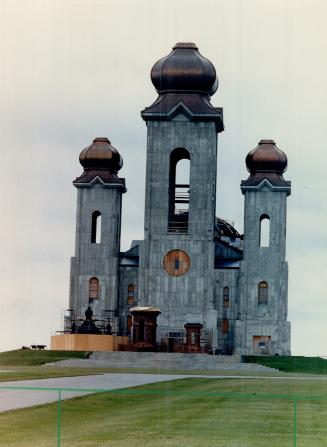 Impressive sight: Inside (top), workmen are dwarfed by the vastness of the church, and the outside is no less impressive with the copper-tiped spire rising majestically