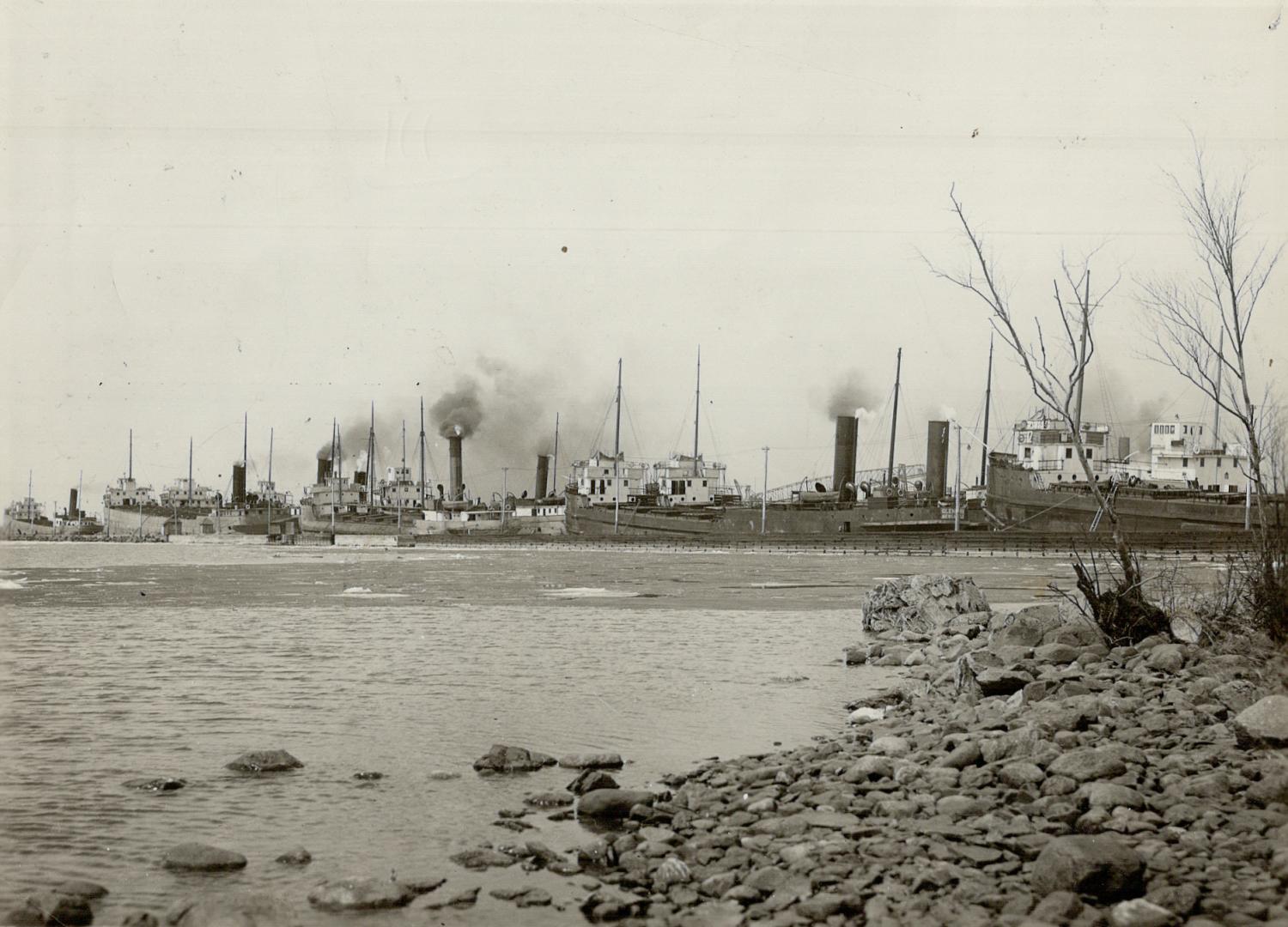 Taken from the shore, this picture shows a number of industrial buildings with many smokestacks…