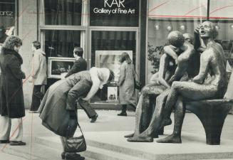 Passerby takes a closer look at sculpture outside Colonnade on Bloor St