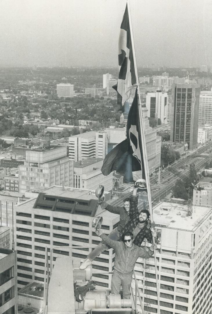 458 feet up, Blackie St. Denis (top), Wodie Meaney and Doug Sumner raise the flag today to signal completion of inner core of the Toronto-Dominion Centre's 35-storey third tower