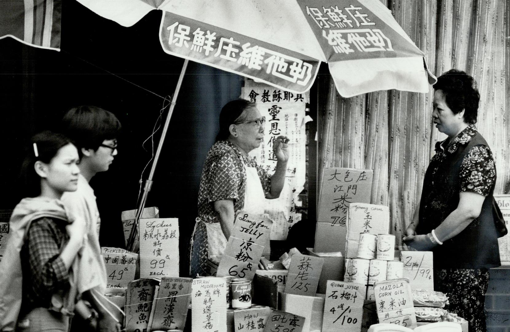 Passing the time: In the crowded, bustling streets of Chinatown, there's still time out for a quiet chat between storekeeper and passerby