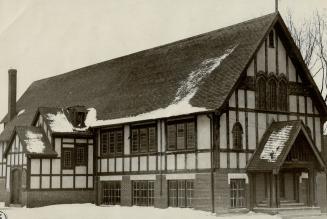 Church with steeply pitched shingle roof and Tudor style construction beams.