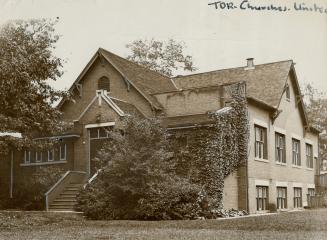 Exterior of small brick church with gable roof, steps leading up to covered entrance and sash w…