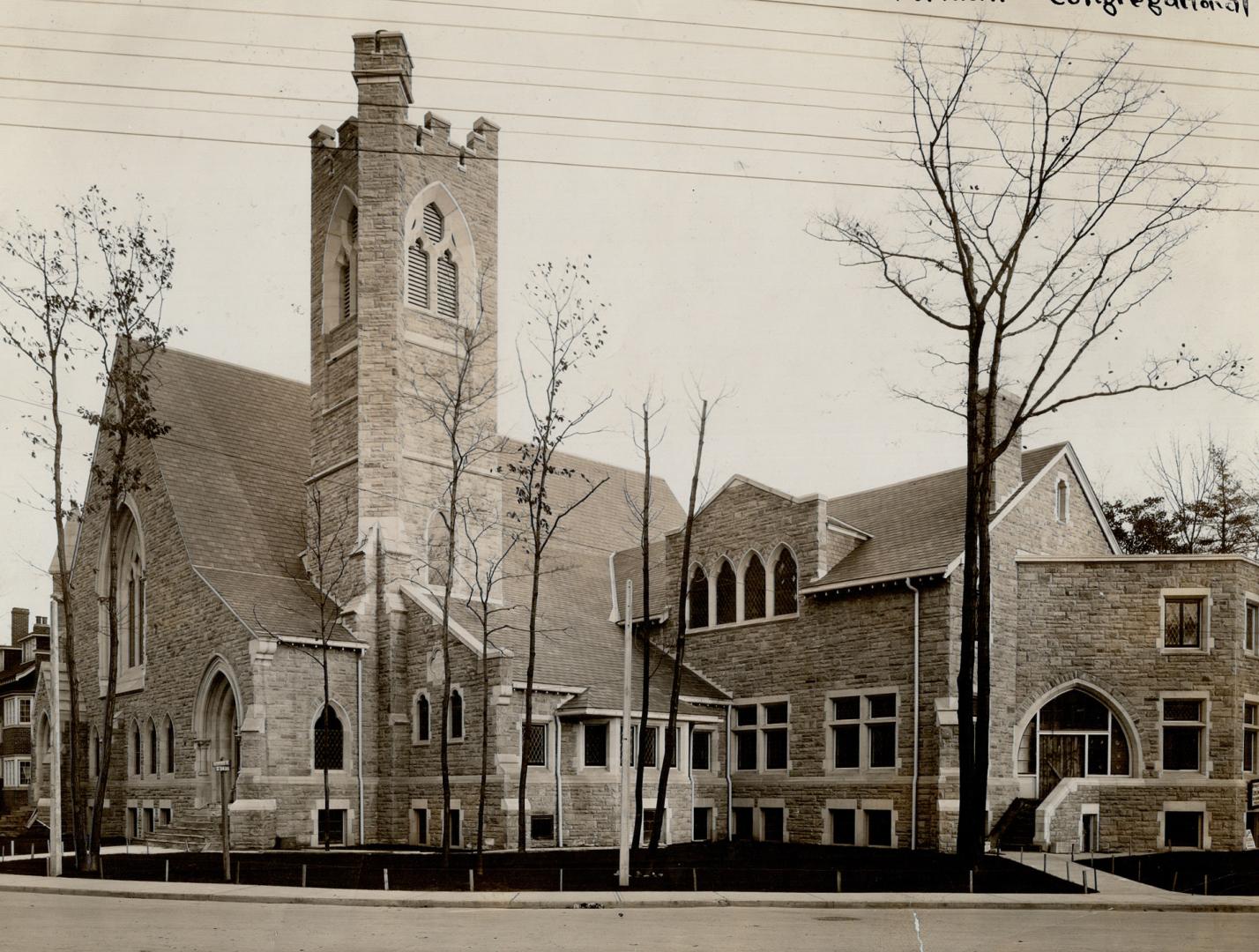 Exterior of brick church with chiseled stone walls, gable roof and belfry tower with crenellati…