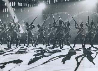 Fort york guard, silhouetted against the lights at Toronto's new city hall, put on a demonstration last night for the thousands of persons who visited(...)