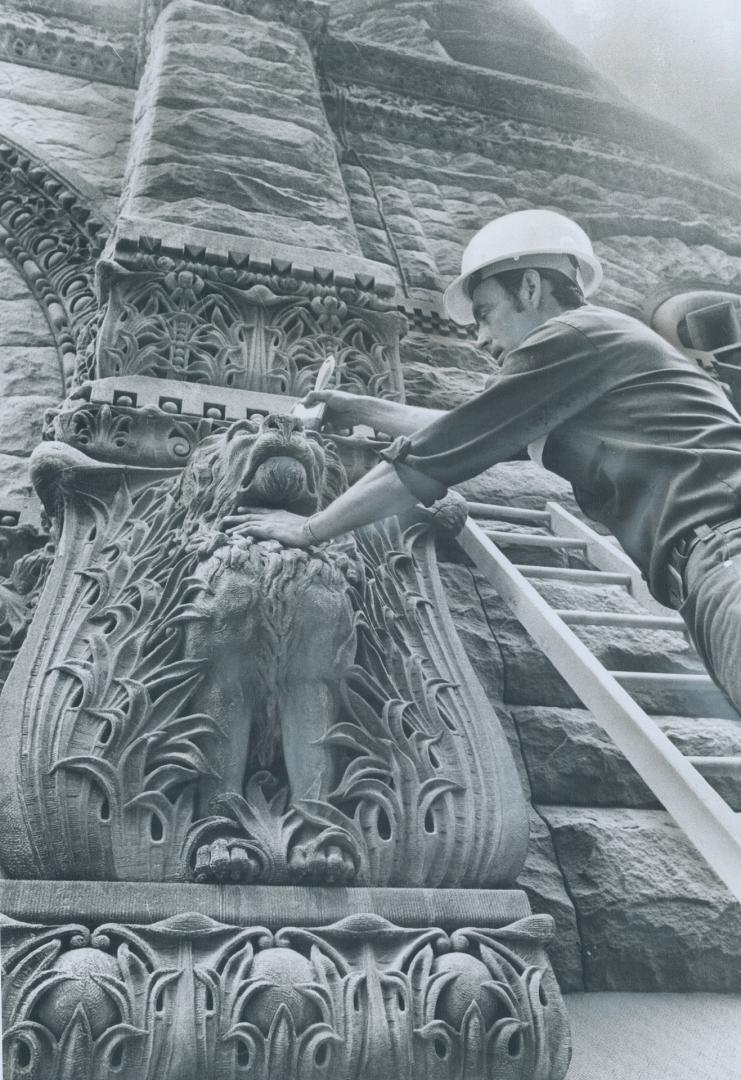 Near the Queen St. entrance to old city hall, foreman Leo Cleutt brushes accumulated sand out of a gargoyle