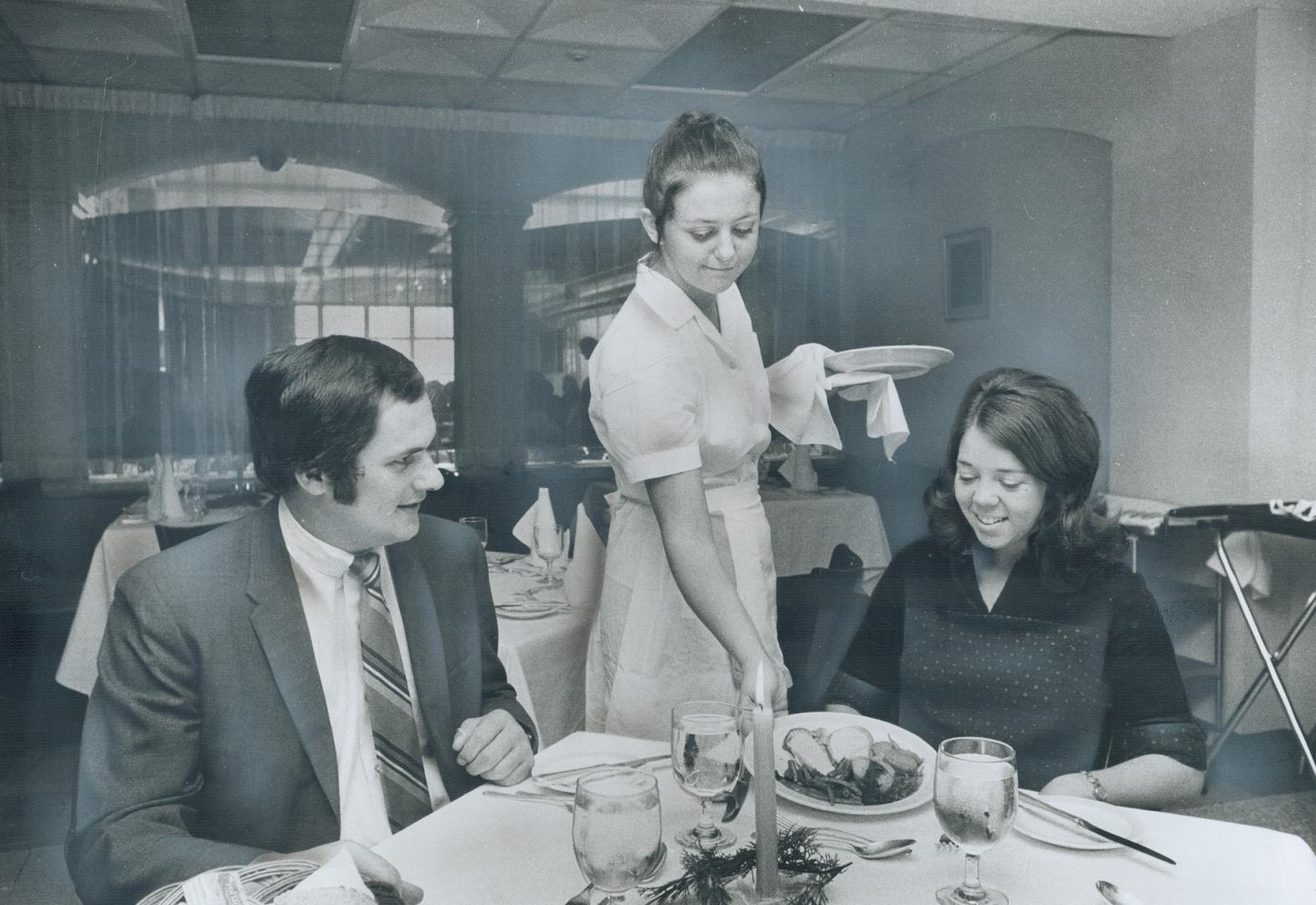 In students' dinning-room at George Brown, Peter Bottcher, baking instructor, and Patricia Lyon, technician, are served the complete turkey dinner. Fo(...)