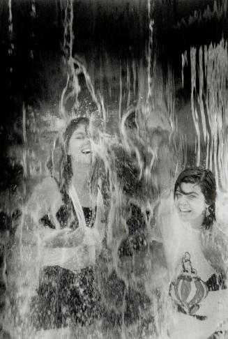 Cool pastime: Kelly Hood, 23, left, and Roisin Cadieux, 23, both of Toronto, find some relief from yesterday's heat under a fountain at the Ex