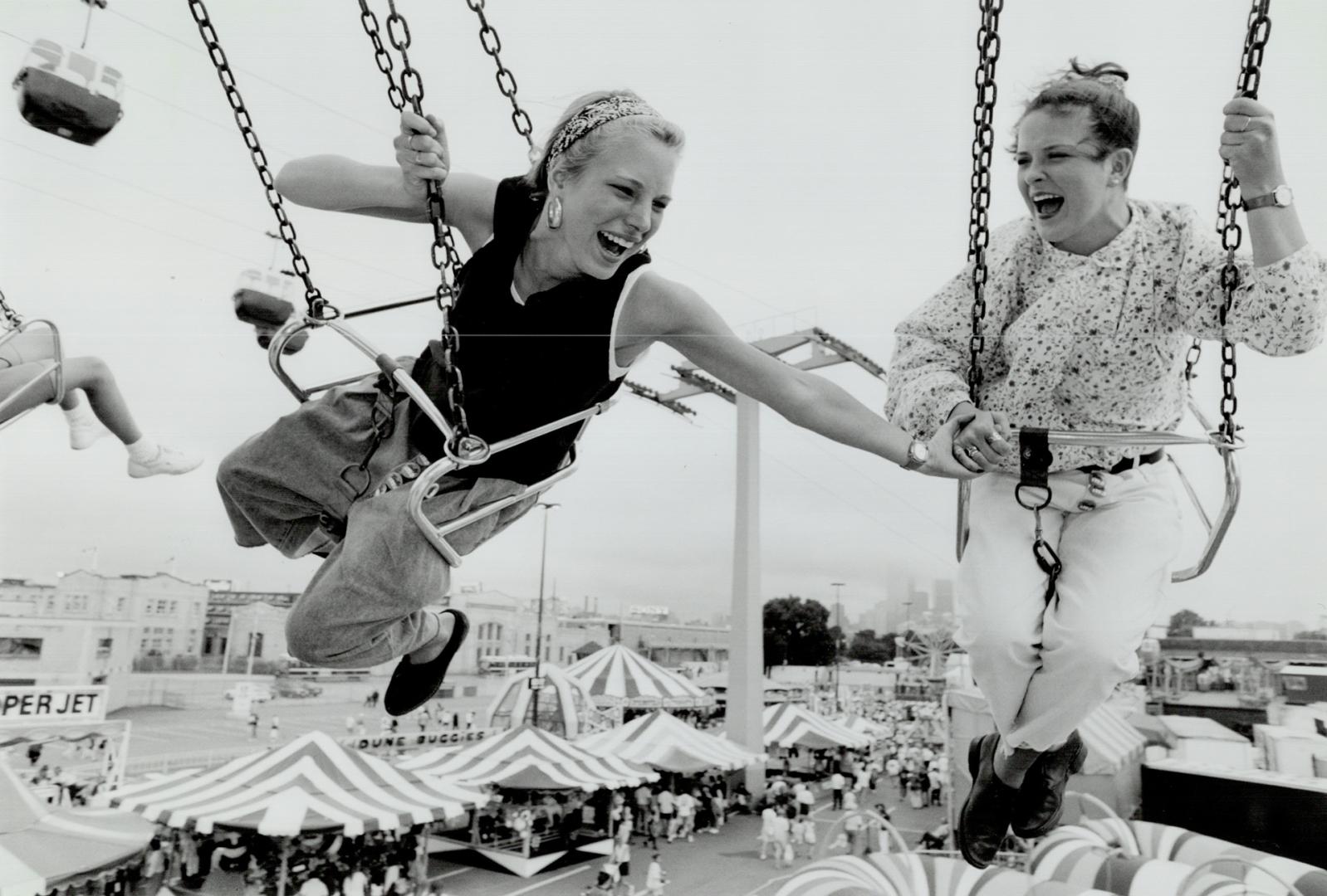 Hanging out at the ex, Jennifer Bertucci, 15, left, grips the hand of Lacey Belanger, 15, as they take a spin on the Wave Swinger ride high above the (...)