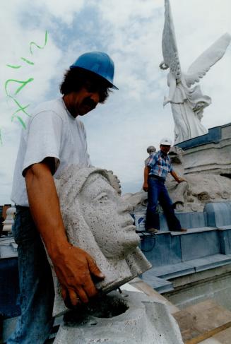 Heady business, Mason Jim Spooner places the restored head on to a figure at the Princes' Gate at Exhibition Place yesterday