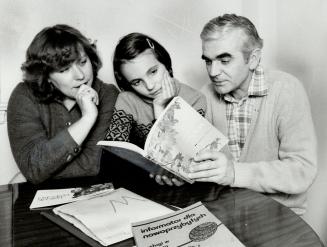 The lucky ones, Krystyna Bienias, daughter Marta and husband Janusz look at book on Canada, their new home