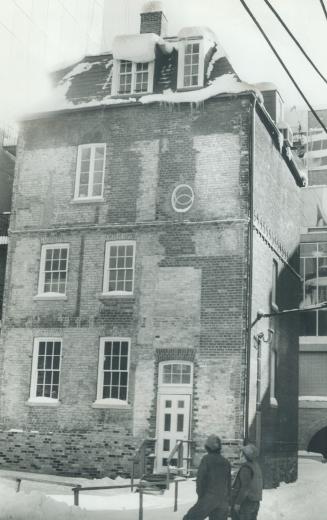 Construction workers from the nearby Centre look at the townhouse built by historian Henry Scadding in 1861 in Trinity Square. It has been saved but (...)