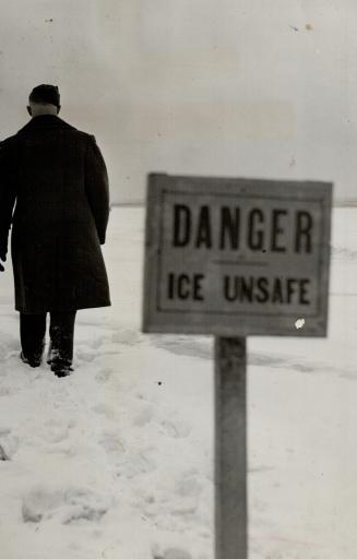 Image shows a gentleman walking on the snow covered lake. There is a sign that reads: Danger. I…