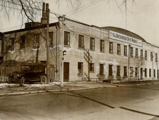 Façade of two-storey brick building with large sign displayed below roofline reading, The Dicki…