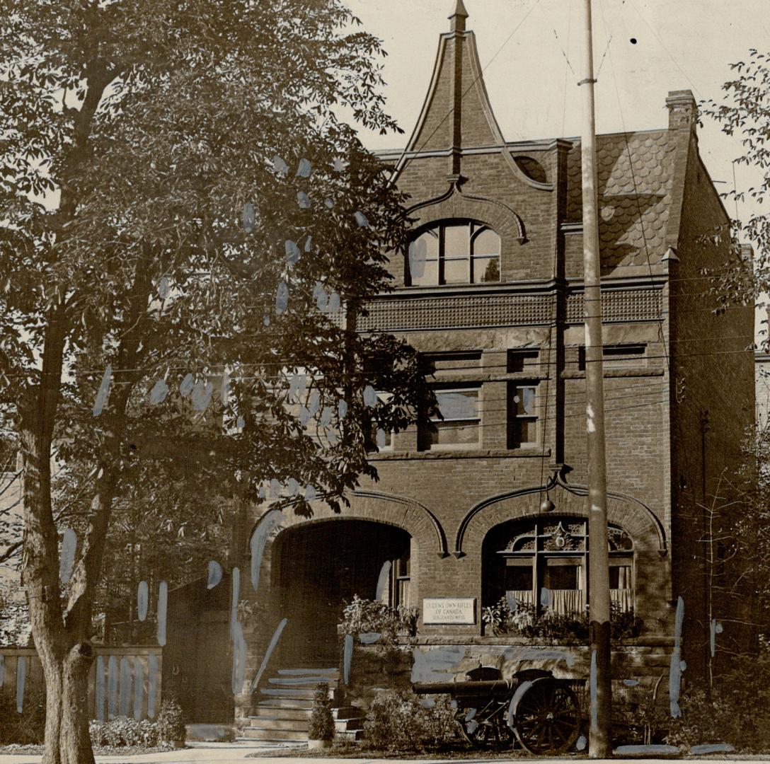 Façade of three-storey brick building with spire above third floor window. 