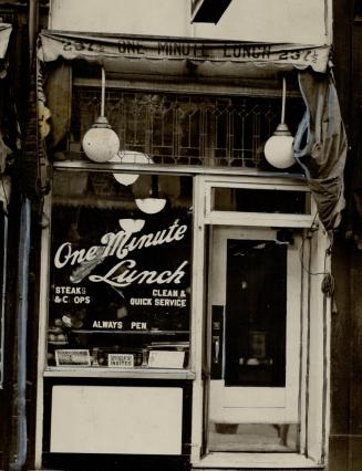 Close-up view of restaurant window and entrance. Wording on window reads: One Minute Lunch, Ste…