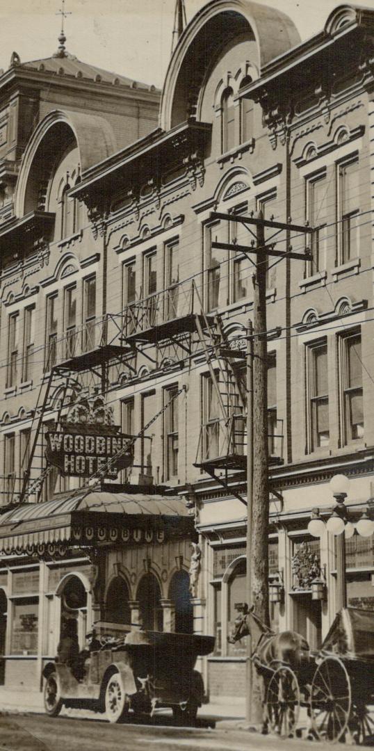 Street view of four-storey building with decorative stonework on façade. A sign overhanging a f ...