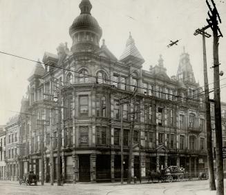 Corner, exterior view of four-storey brick building with turret.