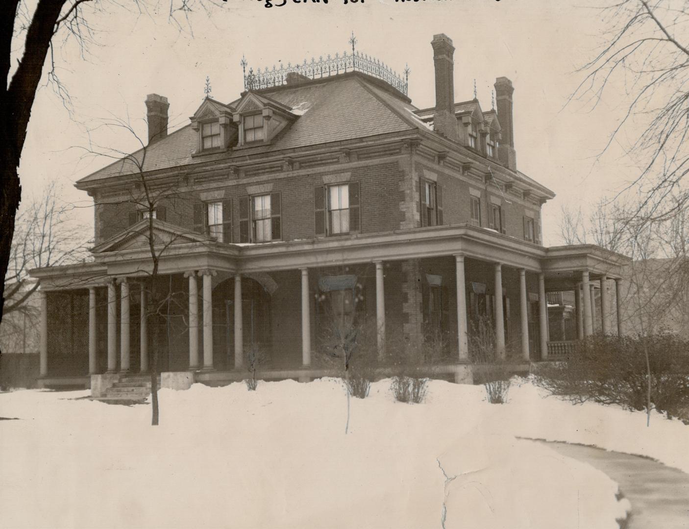 Three-storey structure with gables, brick chimneys and wrap-around porch.