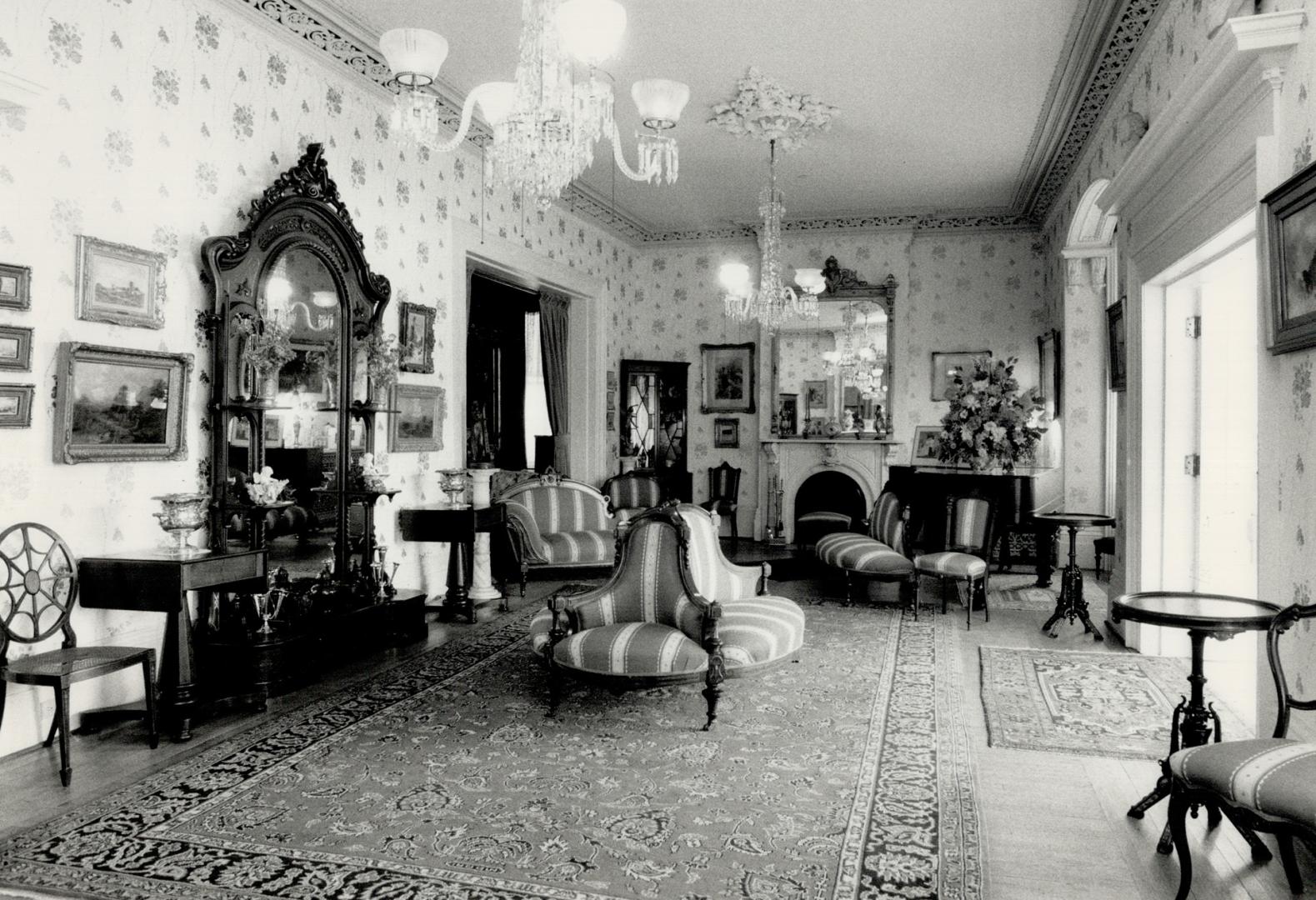 Sitting-room outfitted with wall-mounted art, two large crystal chandeliers, upholstered settee…