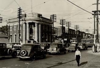 Street view from intersection of two-storey brick building with four pillars at entrance, seen …