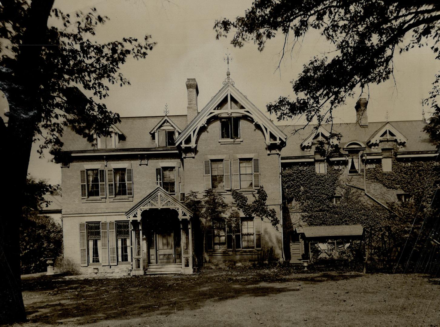 Three-storey light brick house with gabled roof, dormer windows and covered doorstep.