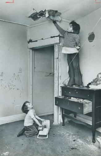 Water overflowing upstairs made the hole in the ceiling 6-year-old Donald Moore points to while his little brother, Stephen, 5, plays on the cockroach(...)