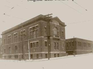 Two-storey brick building at corner. Sign below roof reads, Evangelia Settlement.