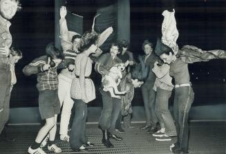 A group of teenagers and a dog standing on a grating to enjoy an up-breeze.