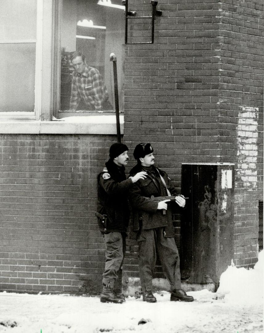 What's going on out there? A curious onlooker watches two police offices from the emergency Task Force as they stand at the ready yesterday with an Uz(...)