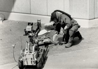 Police examine suitcace 'Bomb' An emergency task force officer examines items in a suitcase that was blown up outside downtown's 52 Division by a robo(...)