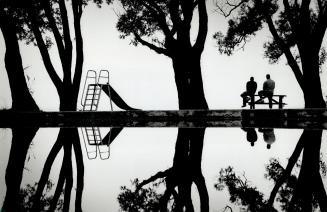 Reflection of a wet summer. An unusually quiet children's wading pool casts a perfect reflection of Budapest Park on Toronto's western waterfront at M(...)