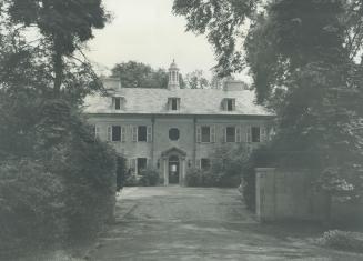 Image shows a two storey building surrounded by trees.