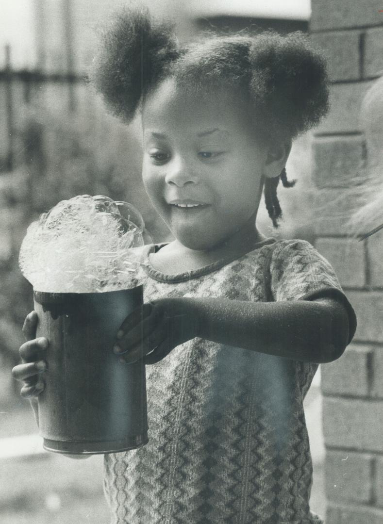 Her own pail of bubbles to play with fascinates this little girl