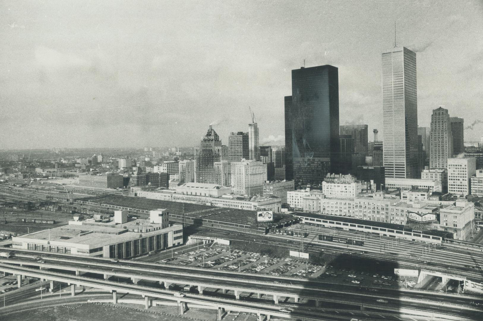 Image shows railroad tracks and the Harbour buildings behind them.