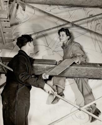 Clinging to the precarious scaffolding, Allen Wargon hands a fellow artist, Pte