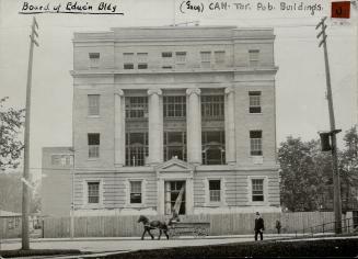 Exterior of four-storey, flat roofed, light coloured brick building with inset pillars above th…