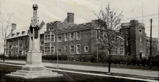 Exterior of three-storey brick building with casement windows and wall parapets. Attached left …