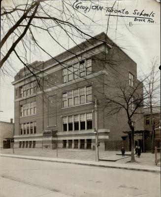 Street view of exterior of three-storey brick building with double-hung windows. Right, three s…