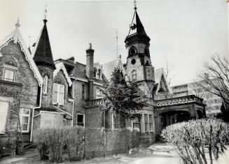 Three-storey brick structure with various levels of gable roof, including two turrets; stone po ...