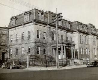 Three-storey stone building with mansard roof and multiple dormer windows.