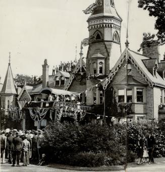 Three-storey brick structure with multi-level gabled roof, dormer windows and two turrets. Smal…