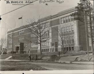 Exterior of four-storey brick building with double-hung windows. The Ontario flag hangs from fl…