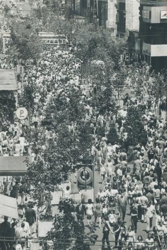 Queen St. streetcar moves slowly across Yonge St. today as lunchtime crowds wander through mall from King to Albert St. Closing off Yonge and replacin(...)